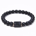 Macro shot of Scorpio black onyx beaded bracelet with engraved sign and bronze metal rings - Scorpio