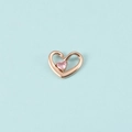 Gros plan du pendentif cœur en or rose avec pierre de naissance rose sur fond bleu - Or Rose Octobre