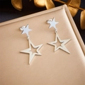Detailed view of silver stainless steel star pendant earrings on a golden display - Double Layer Pentagram Style (E5753 Steel Color)