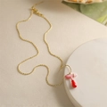 Vue détaillée du collier doré avec pendentif abstrait en émail rose et rouge sur socle - Style-T