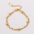 Macro detail of 18KGP gold double-layer chain bracelet with polished gold beads and lobster clasp - Gold