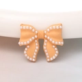 Detail of apricot bow charm with white pearl border for DIY jewelry and phone cases - Yellow