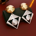 Makroaufnahme geometrischer zweifarbiger Metallohrringe mit Goldstecker und Silberrahmen - Gold- und Silber-Zweiton (Silberstift)