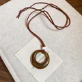 Collana con pendente rotondo in resina e perline di legno vintage su un libro - caffè
