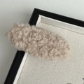 Gros plan d'une barrette à cheveux en peluche beige sur un plateau en tissu doux - Abricot