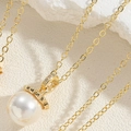 Vista macro di una collana dorata con grande ciondolo di perla bianca e zirconi lucidi - Collana Di Perle Con Cappuccio A Fiore (Oro)
