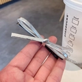 Metallic silver leather bow hair clip with black duckbill grip held in hand - Silver