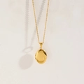 Polished gold-tone oval locket necklace with delicate cable chain on white backdrop - Necklace - Gold Oval / Glossy
