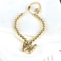 Detail of adjustable gold beaded bracelet featuring a shimmering letter W zircon charm - Letter W
