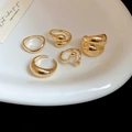 Minimalist five-piece golden ring set with irregular liquid metal texture on white ceramic plate - Style 9 (Set of 5)