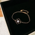 Détail d'un bracelet fleur doré avec perle présenté dans un coffret en velours noir - Bracelet / Doré