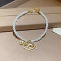 Detail of a pearl bracelet with a golden rocking horse charm on a textured background - Gold Pony Pearl Bracelet