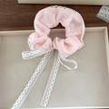 Dettaglio di scrunchie rosa con pizzo bianco e lunghi nastri su un vassoio - Rosa