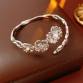 Vista macro de la pulsera floral plateada con perlas y circones en caja de cuero - Plateado