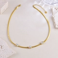 Elegante gouden schakelketting met drie iriserende rechthoekige edelstenen op een beige ondergrond - Ketting
