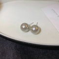 Macro shot of large round grey pearl stud earrings with smooth metallic silk texture - 14mm