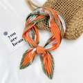 Pleated square neckerchief in orange and green floral pattern tied in a knot - Orange Cross Flower