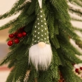 Dettaglio di uno gnomo di Natale in maglia verde appeso a un albero con bacche rosse - Pendaglio in Maglia Verde Stile A