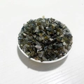 Natural labradorite crystal chips in white bowl featuring dark green and grey iridescent tones - Labradorite