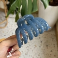 Detailed view of the blue glossy spiral hair claw clip held against an outdoor background - Haze Blue