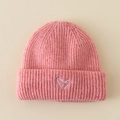 Close-up of pink knit baby hat featuring a purple embroidered heart and ribbed cuff detail - Hat / Pink
