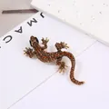Detailed close-up of golden lizard brooch with amber crystals and black gemstone eyes - Coffee