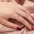 Elegant gold wavy ring with white zircon stones worn by a model on pink silk background - SE797 Trend Chart Shape