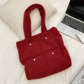Dark red plush tote bag with four front pockets and colorful snap buttons on white bedding - Christmas Red