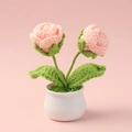 Nahaufnahme einer handgehäkelten rosa Rose im Keramiktopf mit zwei gestrickten Blütenknospen - Doppelkopf-Rosen-Topfpflanze / Fleischrosa