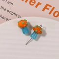 Macro shot of colorful glass mushroom beads with dots on a white textured plate - No.5 (Orange Cap Blue Stem)