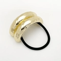 Detail eines minimalistischen goldenen Haargummis mit unregelmäßigem Metallring - Gold
