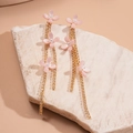 Dettaglio di orecchini a fiore rosa con catene a nappa dorate e piccole perle - Rosa