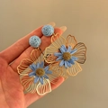 Close-up of blue raffia flower earrings with gold-toned metal petals held in hand - Vacation Style Flower (Silver Post) / Blue