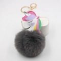 Detalle macro de un unicornio de cuero PU de colores y un pompón de pelo gris del llavero - gris oscuro
