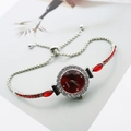Detailed macro view of silver quartz watch with red gems and adjustable pull cord - Silver Red