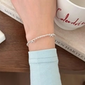 Elegante bracciale in argento s925 con ciondoli a fiocco, indossato al polso su tavolo in legno - Bracciale Pepite d'Argento con Fiocco (Argento) / Argento 925