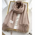 Close-up of oatmeal cashmere scarf with fine fringe tassels and minimalist brand label - Oatmeal