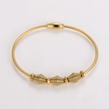 Vista detallada de pulsera de cable dorado con tres cuentas de espiral y cierre - Brazalete Dorado Con Cierre de Inserción / Dorado