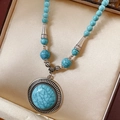 Primer plano del collar étnico de cuentas turquesas con colgante floral de plata antigua - Estilo Turquesa Azul / Azul