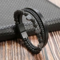 Macro detail of men's leather bracelet showing Tree of Life charm and black magnetic clasp - Black + Volcanic Stone