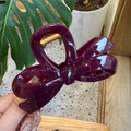 Detail of a large glossy deep purple bow-shaped hair claw clip with gold metal spring mechanism - 10.5cm / Cherry Red