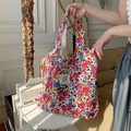 Dettaglio di una borsa shopper in tela floreale tenuta sopra un tavolino bianco - Fiori Colorati