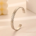 Detail of silver stainless steel open bangle featuring continuous leaf pattern engraving - Silver Leaf