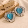 Detail of silver heart stud earrings featuring light blue cat eye stones and ruffled edges - Lake Blue