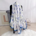 Vue détaillée d'une longue écharpe en soie aux motifs floraux bleus sur une chaise grise - Bleu