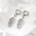 Polished silver titanium steel feather earrings in leaf design on a textured white background - Steel