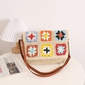 Handgefertigte Stroh-Umhängetasche mit buntem Häkel-Granny-Square auf weißem Tisch - Beige