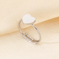 Detalle de anillo ajustable de corazón plateado sobre fondo de seda dorada - Corazón Color Acero (KR106173-K)