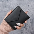 Minimalist black pebbled leather mini wallet with envelope flap held in hand - Black