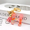 Macro detail of resin letter H keychain with pink glitter and gold bee charm - Letter H Bee Keychain